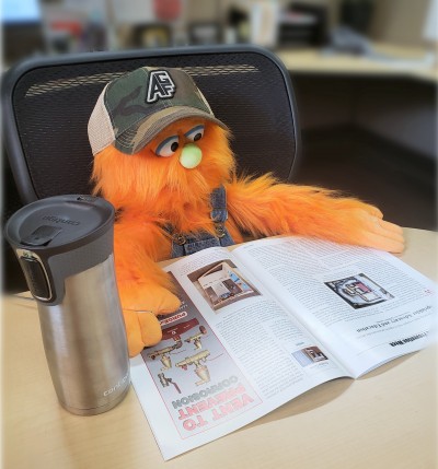 Puppet Testy McSprinkles sitting at a desk to read a magazine